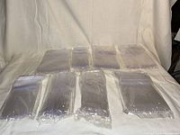 Multiple unopened packs of clear plastic Solo cups and paper plates arranged on a plain background