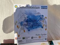 Box showing the Smithsonian Robo Spider STEM toy, featuring blue transparent plastic body, multiple legs, and branding.