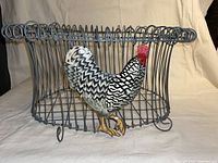 Front view of the vintage wire egg basket showing the decorative painted chicken figure attached on one side.