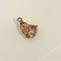 Top view showing the textured, irregular natural nugget shape and attachment loop of the 10K gold charm.