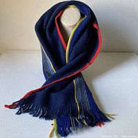 Image showing scarf displayed on a mannequin to highlight drape, colors, and fringe detail.