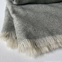 Close-up of the grey wool blanket showing fine texture and cream fringe.