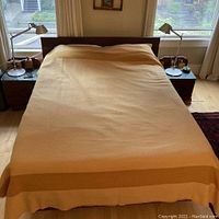Full view of buttery colored wool blanket spread over queen size bed showing overall design and size.