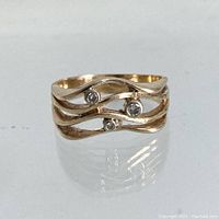 Front view showing three round diamonds set within the wavy ribbon bands