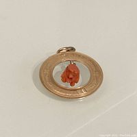 Close-up photo of the front showing 14K gold circular open center charm with coral flower dangle and engraved design