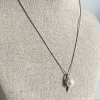 Necklace displayed on mannequin showing pendant hanging at center.