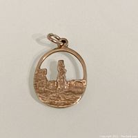 Front view of the oval 9K gold charm with relief Stonehenge design