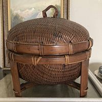 Front view of the domed bamboo wicker basket on pedestal base showing the woven detail and construction.