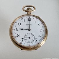 Front view showing white enamel dial with black Arabic numerals, subsidiary seconds at 6, blued steel spade hands