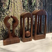 Front angled view showing all three teak wood abstract sculptures arranged side by side on a marble surface with textured backdrop.