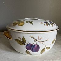 Side view of the Royal Worcester Evesham lidded casserole showing fruit design and gold handles.