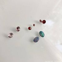 Overview of all eight stones (two opals, two pink faceted, four red faceted) on white background