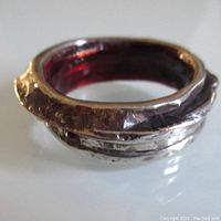 Close-up front view of vintage cast silver ring with blackened finish and brass detail