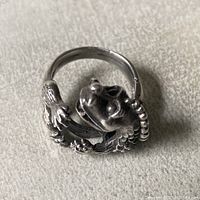 Sterling silver dragon ring showing detailed dragon head and claws wrapped around the band on textured background.