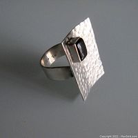 Side angle showing the hammered rectangular face of the sterling silver ring with black onyx stone and the open band size 8