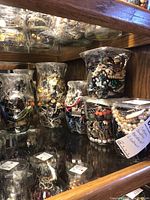 Wide view showing six clear plastic containers filled with assorted costume jewelry items including beads, metal chains, and various styles of bracelets and necklaces.