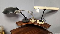 Wide view showing all three vintage desk lamps on a wooden surface against gray wall.