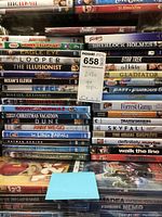 Photo shows a larger collection of DVDs stacked including titles like Avengers, St. Elmo's Fire, Sherlock Holmes, Star Trek, Gladiator, Forrest Gump, Fast & Furious 6, Skyfall, Transformers, The Usual Suspects, and more.