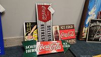 All four Coca-Cola enamel signs arranged together, showing design and size comparison.