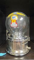 Front view of Ford gumball machine showing clear glass globe with residue and chrome base with coin slot and handle.
