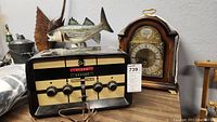 Photo showing vintage security system console and mantle clock side by side on a table