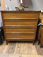 Full front view of the Dixie four drawer chest with wood panel drawer fronts and tapered legs.