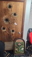 Overall view of brass burst wall art standing against wood door with casino-themed sign in front.