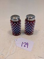 Pair of cranberry colored hobnail opalescent glass salt and pepper shakers with silver metal screw-on tops