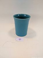 Front view of turquoise ceramic utensil holder with slight flare and horizontal ridges.