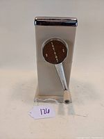 Front view of Mid Century Ice-O-Mat ice crusher showing the brown circular dial labeled 'ICE-O-MAT' and chrome hand crank.