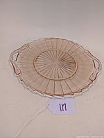 Top-down photo showing pink Depression glass tray with molded radial and starburst pattern and two handles on sides.