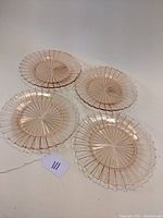 Four pink Depression glass dinner plates arranged to show entire set and pattern.
