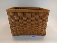 Side view of the rectangular woven basket with wooden frame on top.
