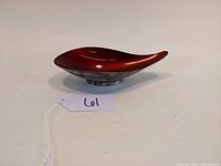 Curved silver plated dish with red enamel interior viewed from above showing glossy enamel and smooth finish.