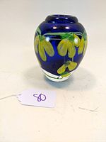 Studio art glass paperweight or vase with cobalt blue base and yellow floral decoration, shown from the front left angle.