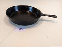 Front angle showing the skillet with handle and pouring spout, tagged with a lot number tag.
