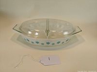 Oval vintage Pyrex vegetable dish with turquoise snowflake design and clear glass lid in place.