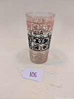Single vintage Anchor Hocking tall glass tumbler showing pink scroll and leaf patterns and central black band with leaf motifs