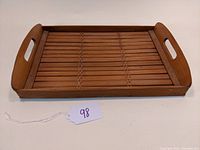 Front and side angle view of the vintage bamboo serving tray showing its shape, handles, and slatted bamboo design