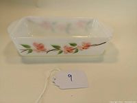 Side view showing pink flower and green leaf decoration on white glass loaf pan