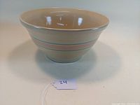 Side view of the beige McCoy pottery mixing bowl showing the pink and blue horizontal bands around its exterior.