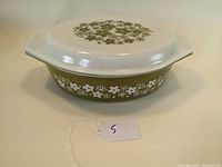 Full view of Pyrex oval casserole dish with lid showing olive floral pattern on exterior and lid.