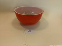 Side view of the vintage red glass mixing bowl showing its red exterior and white interior.