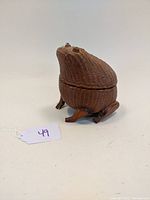 Wicker frog basket viewed from front angle, showing the frog's shape and wooden legs.