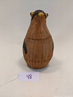 Front view of vintage wicker penguin basket, showing the penguin's head and body.