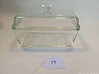 Front and side view of the clear rectangular glass loaf pan with lid and visible light chevron pattern on side.