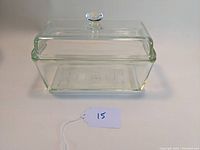 Front view of the rectangular clear glass loaf pan with lid and glass knob handle, showing the chevron pattern along the sides.