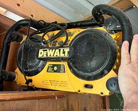 Front view of DEWALT DC0111 jobsite radio showing speakers, control buttons, carry handle, and DEWALT logo.