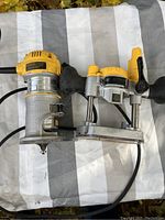Side angle photo showing the entire DEWALT DWP611 router mounted in the plunge base. The yellow motor housing, adjustment handles, and metal base are visible.