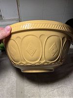 Side view of yellow stoneware bowl showing embossed geometric pattern and ridged rim